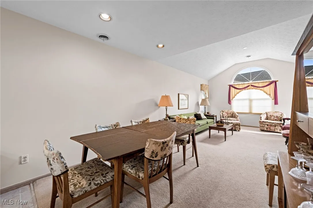 Dining space with vaulted ceiling, light colored carpet, and recessed lighting