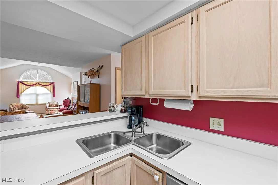 Kitchen with light brown cabinetry, light countertops, and lofted ceiling