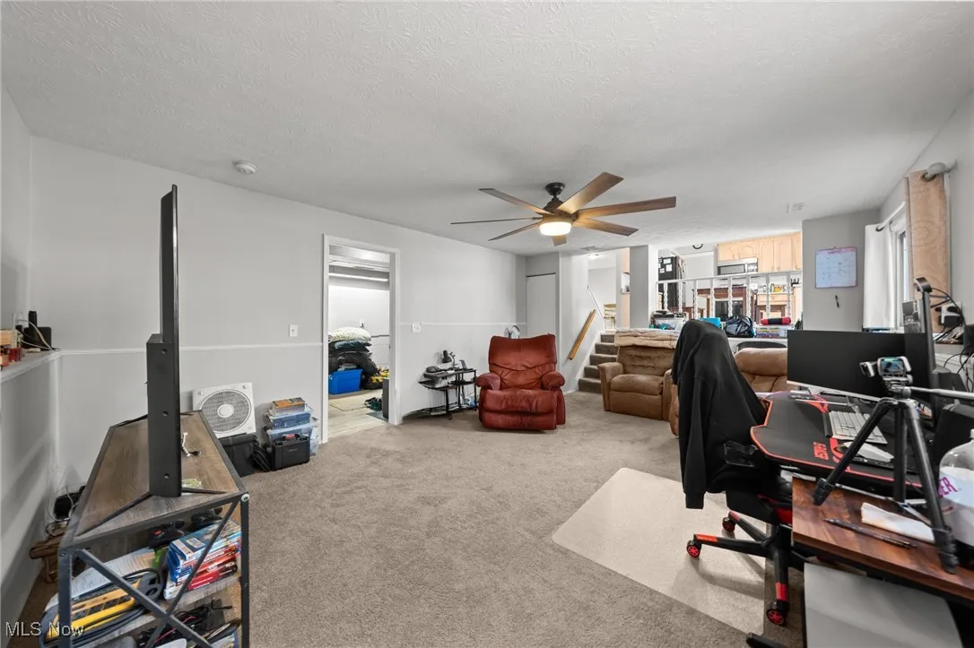 Home office with carpet, a textured ceiling, and a ceiling fan