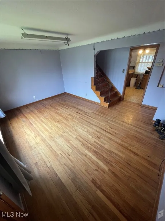 Unfurnished living room with light wood-type flooring and stairway