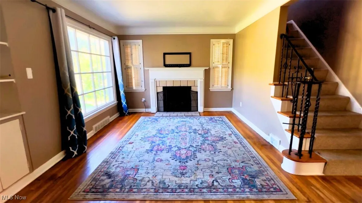 Living area featuring wood finished floors, a tile fireplace, and stairway