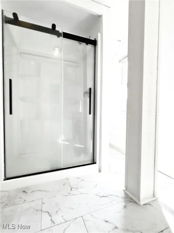 Bathroom with a stall shower and marble finish floors