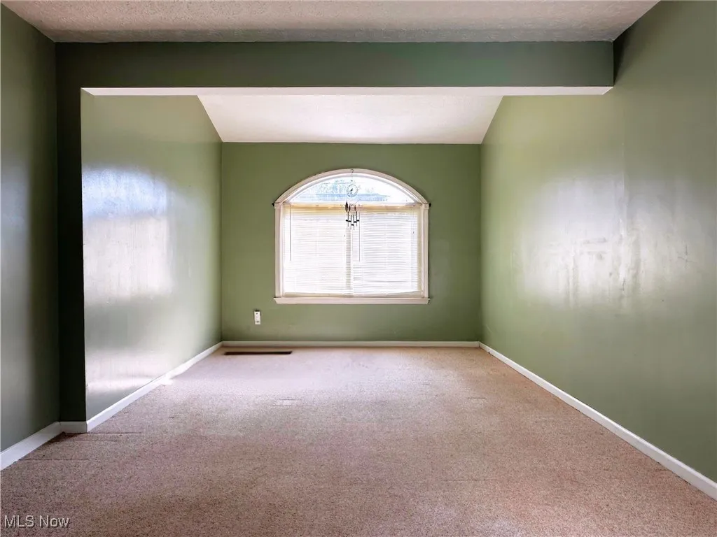 Carpeted spare room with baseboards and a textured ceiling