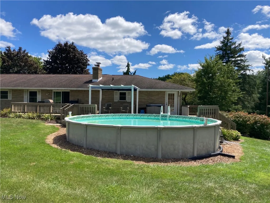 Swimming pool featuring a wooden deck and a lawn