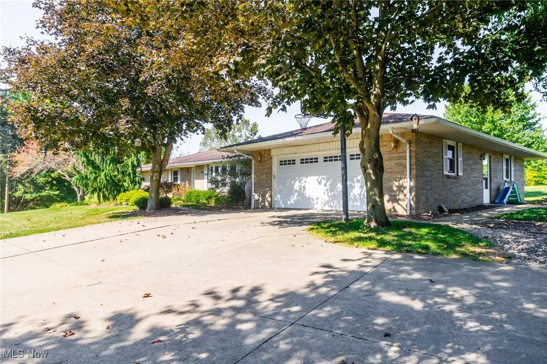 Single story home with brick siding, concrete driveway, a garage, and a front lawn