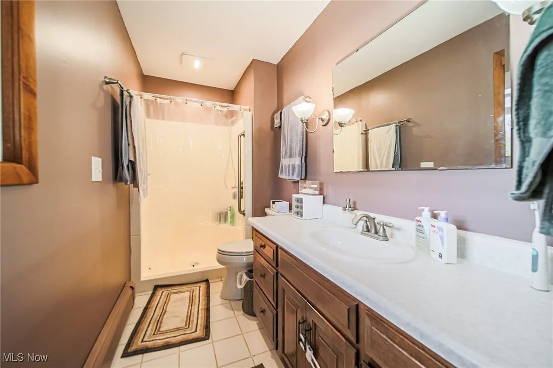 Full bath with a shower stall, vanity, and light tile patterned floors