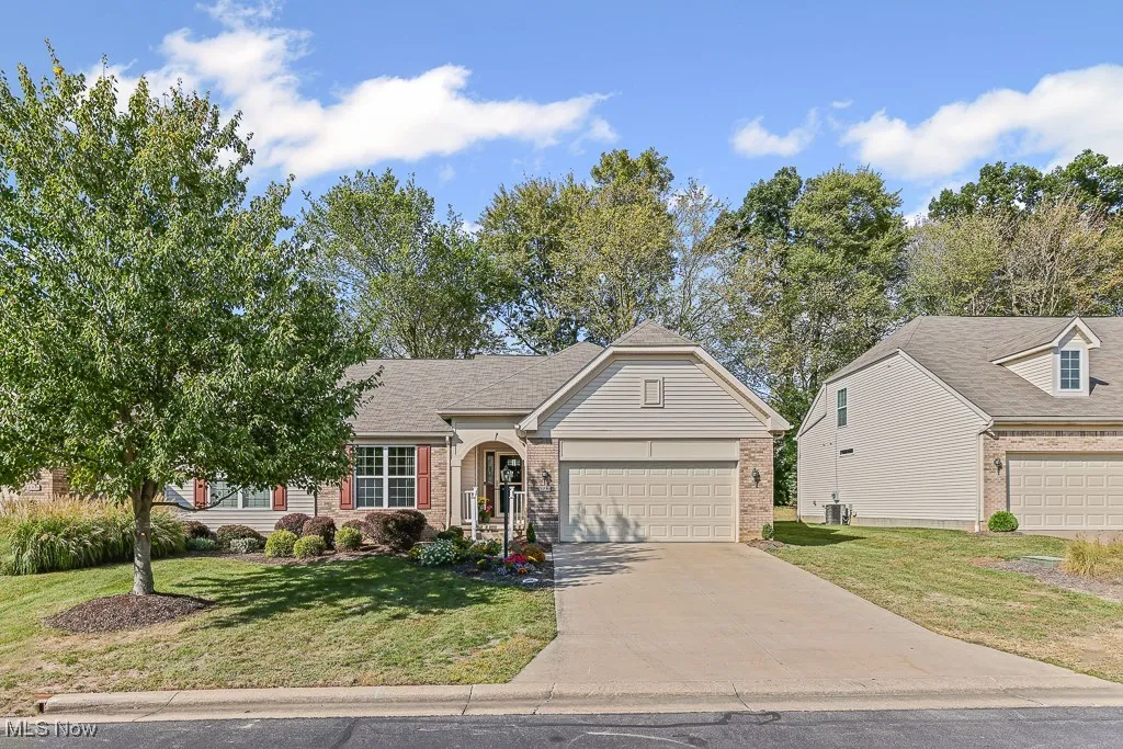 View of front of property featuring brick siding, a front yard, concrete driveway, and an attached garage
