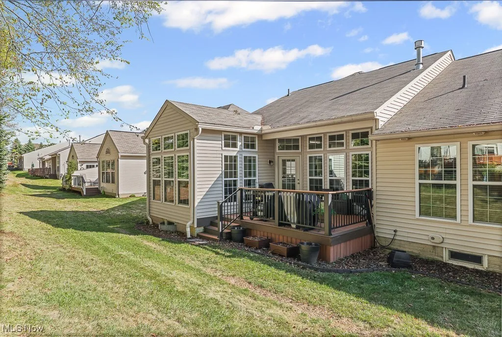 Back of property featuring a deck, a yard, and roof with shingles
