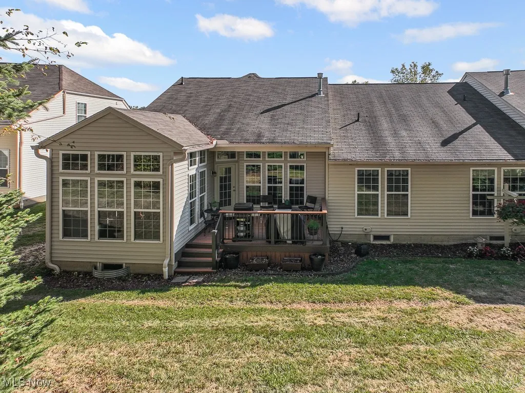 Rear view of property with a deck, roof with shingles, and a yard