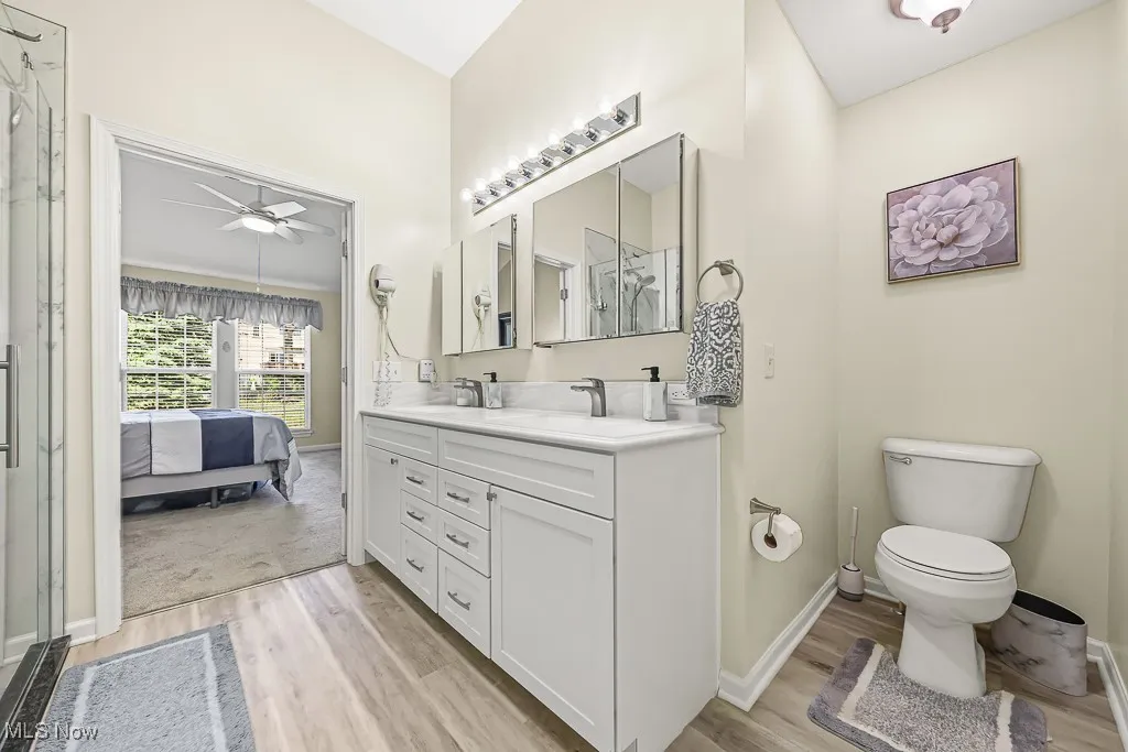 Bathroom with double vanity, ensuite bathroom, light wood-type flooring, a ceiling fan, and a stall shower