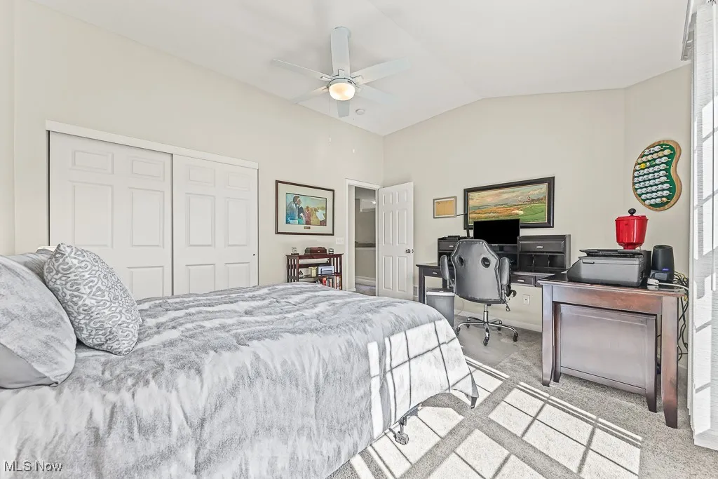 Carpeted bedroom featuring vaulted ceiling, a closet, ceiling fan, and an office area