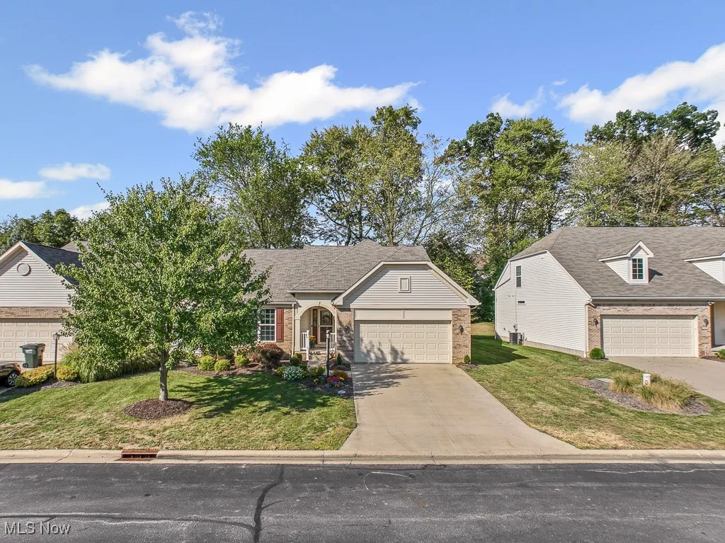 View of front facade with a front yard, brick siding, concrete driveway, roof with shingles, and an attached garage
