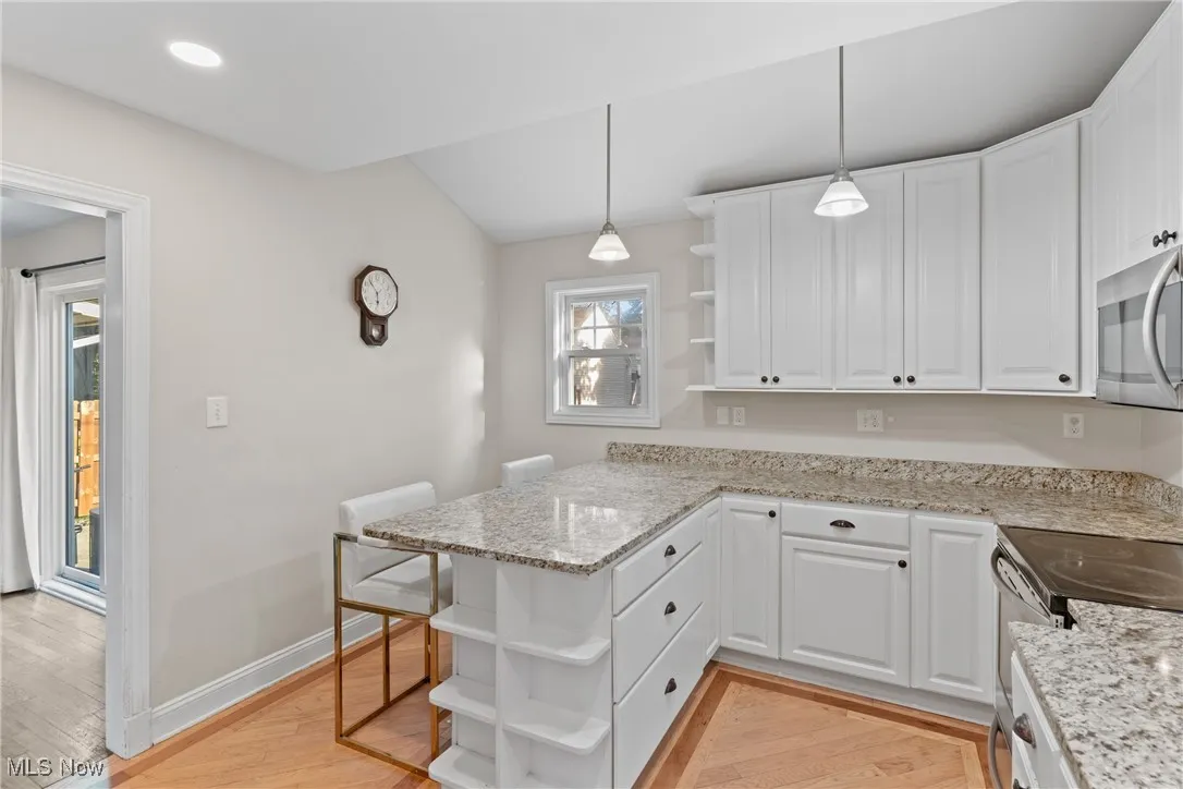 Kitchen featuring open shelves, hanging light fixtures, light stone counters, and recessed lighting