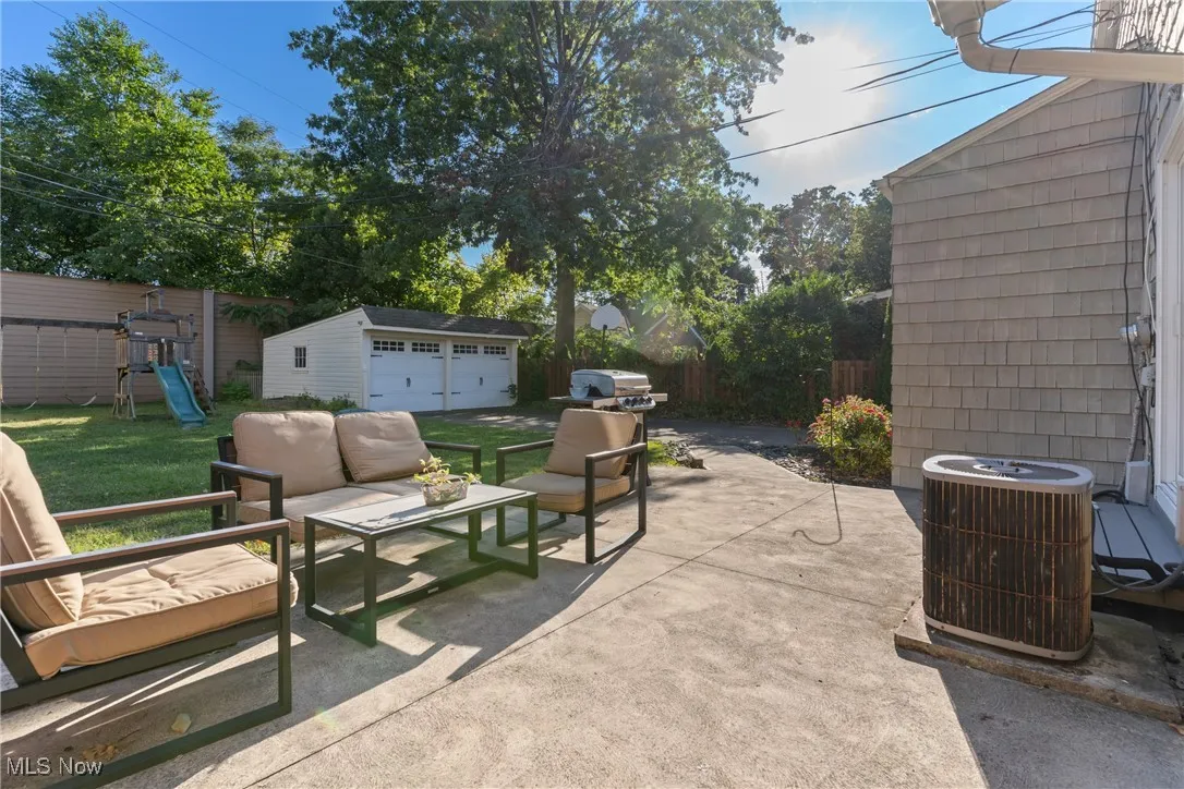 Fenced backyard with an outdoor structure, a patio area, an outdoor hangout area, a detached garage, and a playground