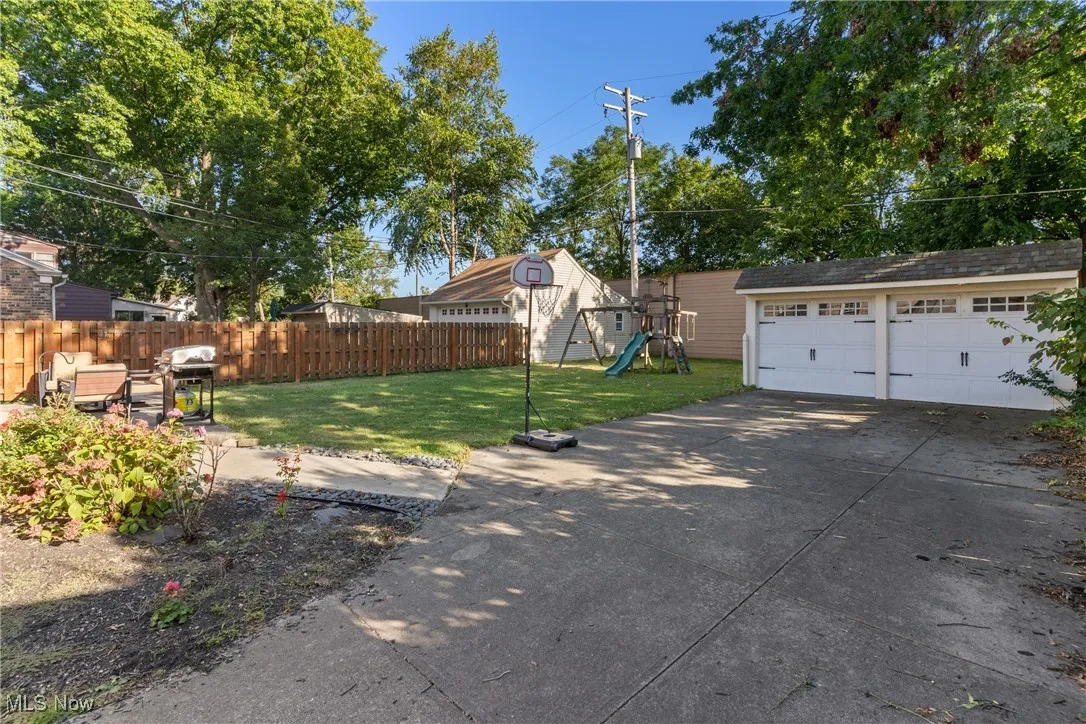 Fenced backyard featuring a playground, an outdoor structure, and a detached garage