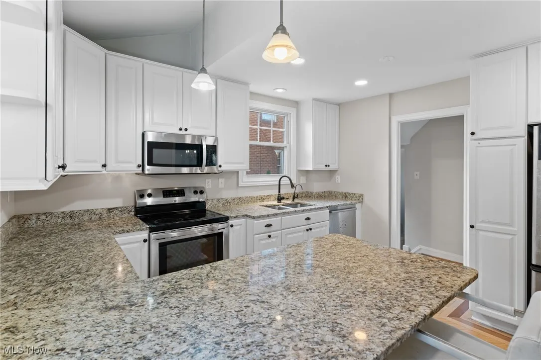 Kitchen featuring light stone counters, appliances with stainless steel finishes, white cabinetry, pendant lighting, and recessed lighting