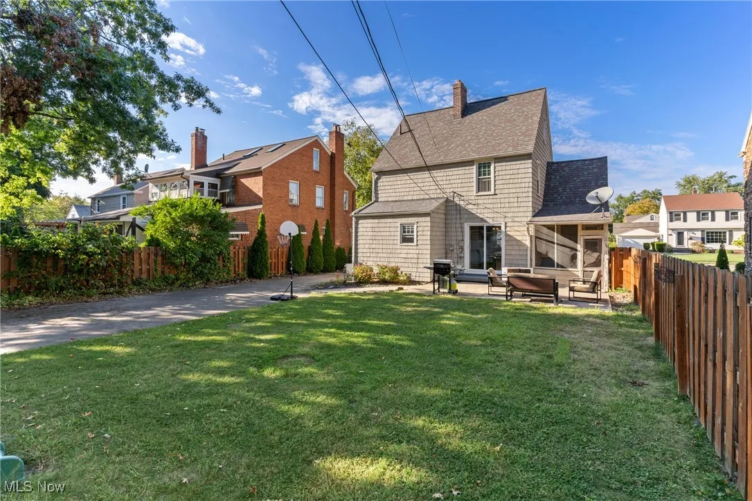 Rear view of house featuring a fenced backyard, a shingled roof, a patio area, and a chimney