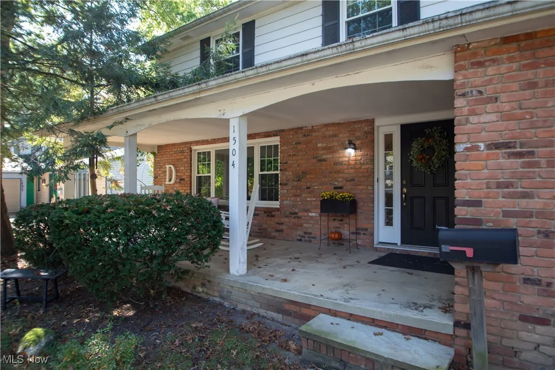 View of exterior entry featuring covered porch and brick siding