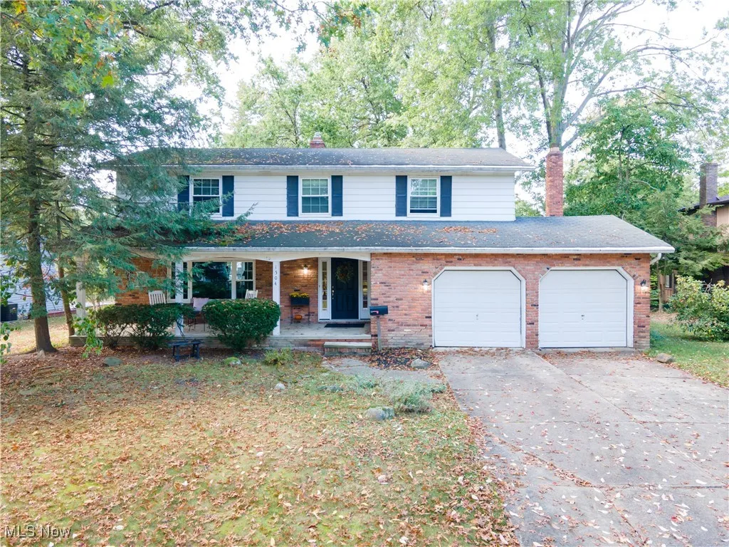 View of front of property with a chimney, covered porch, concrete driveway, and brick siding