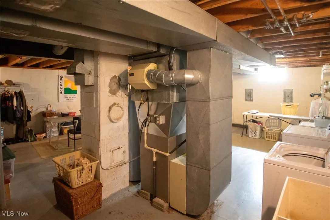 Unfinished below grade area featuring heating unit and washer and clothes dryer