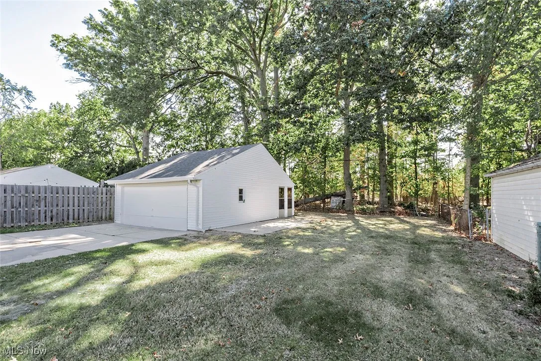 Fenced backyard featuring view of wooded area, an outbuilding, and a garage