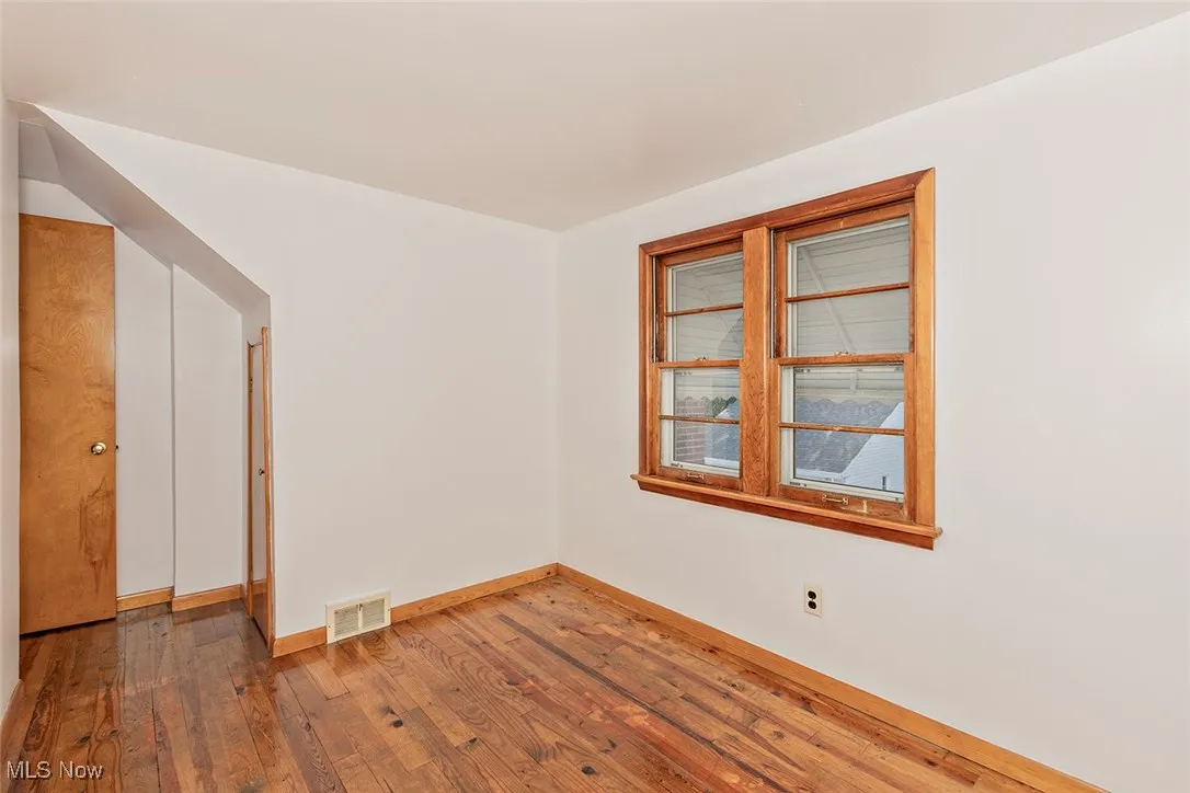 Unfurnished room featuring hardwood / wood-style floors and baseboards