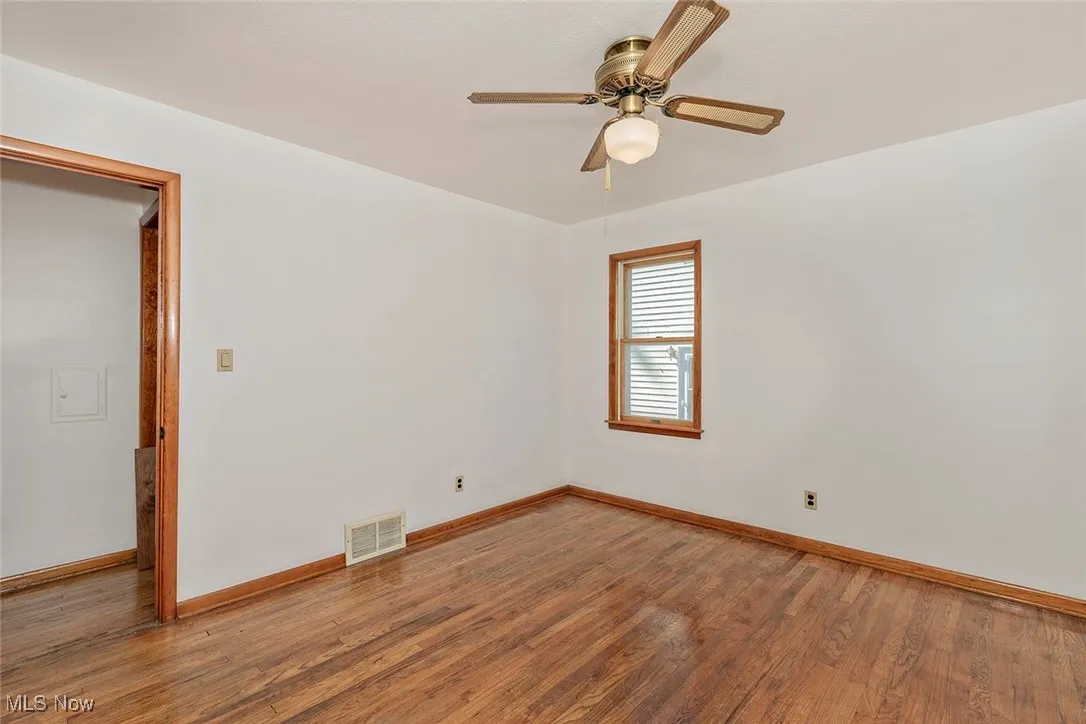Empty room with wood finished floors and a ceiling fan