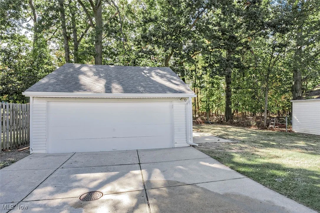 Detached garage featuring view of wooded area