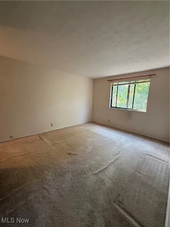 Carpeted empty room featuring a textured ceiling