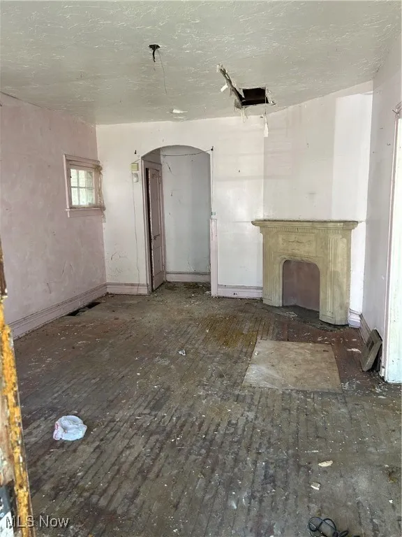 Unfurnished living room with a textured ceiling and arched walkways