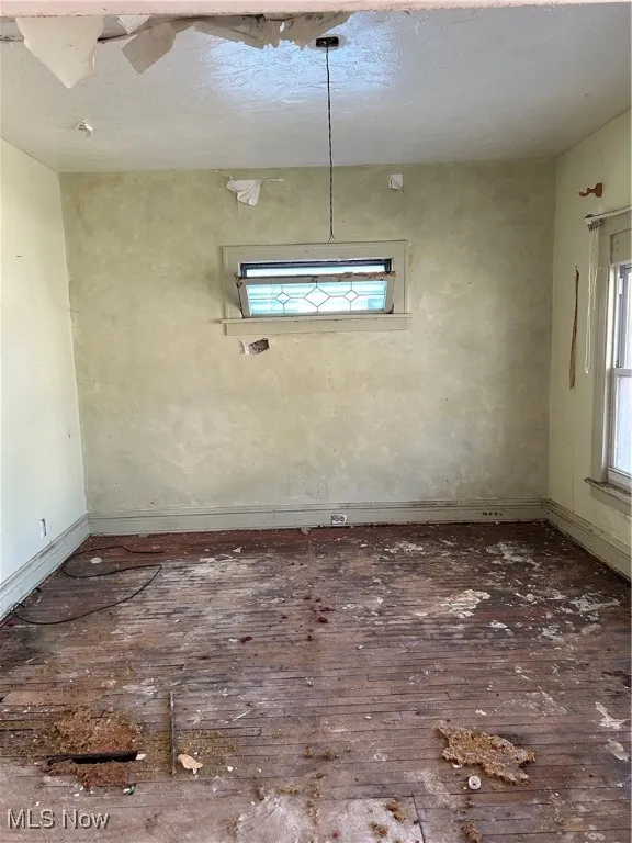 Empty room featuring dark wood-type flooring and baseboards
