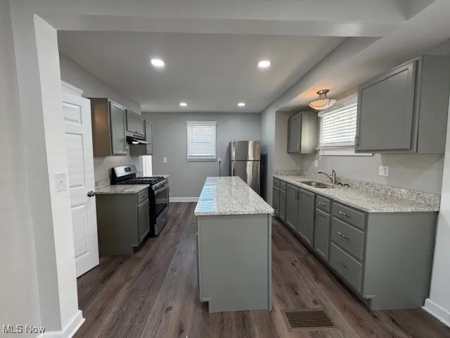 Kitchen featuring gray cabinets, stainless steel appliances, recessed lighting, light stone countertops, and dark wood-style flooring