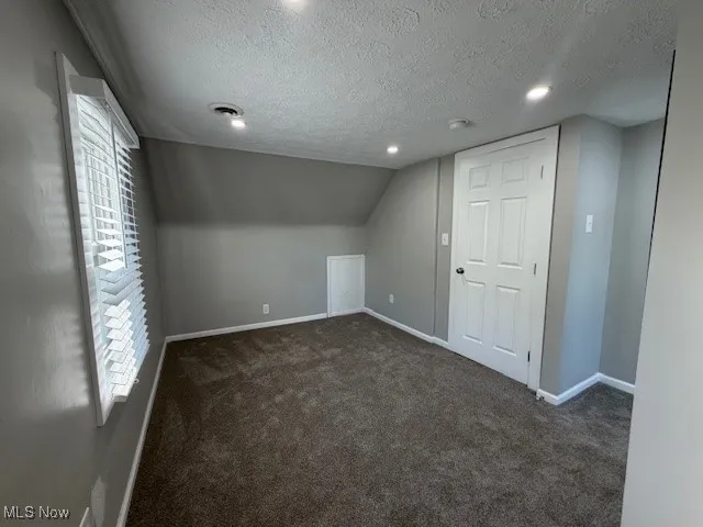Bonus room featuring dark carpet, a textured ceiling, and recessed lighting