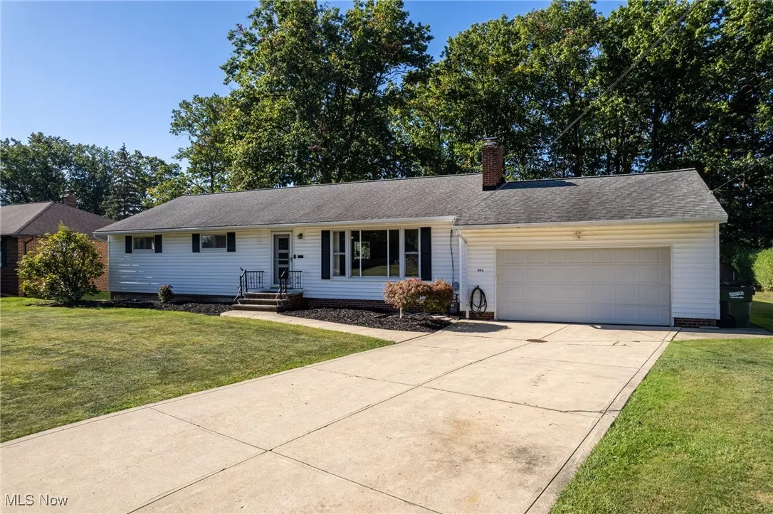 Single story home with a front lawn, a chimney, a garage, and driveway