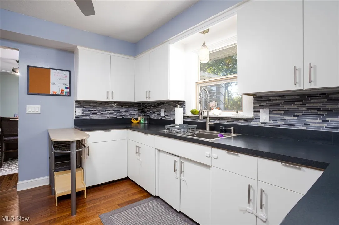 Kitchen with dark countertops, white cabinetry, and dark wood-style floors