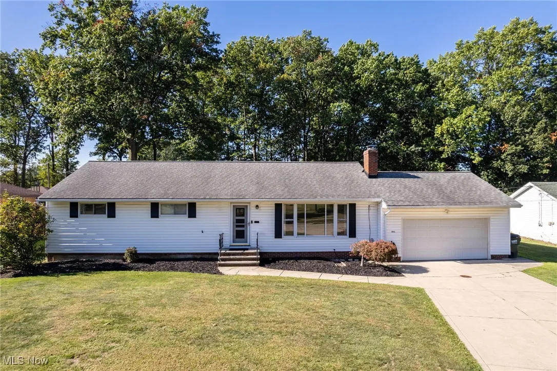 Ranch-style home featuring a front yard, a garage, concrete driveway, and a chimney