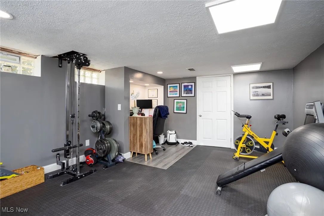 Exercise area with a textured ceiling and baseboards