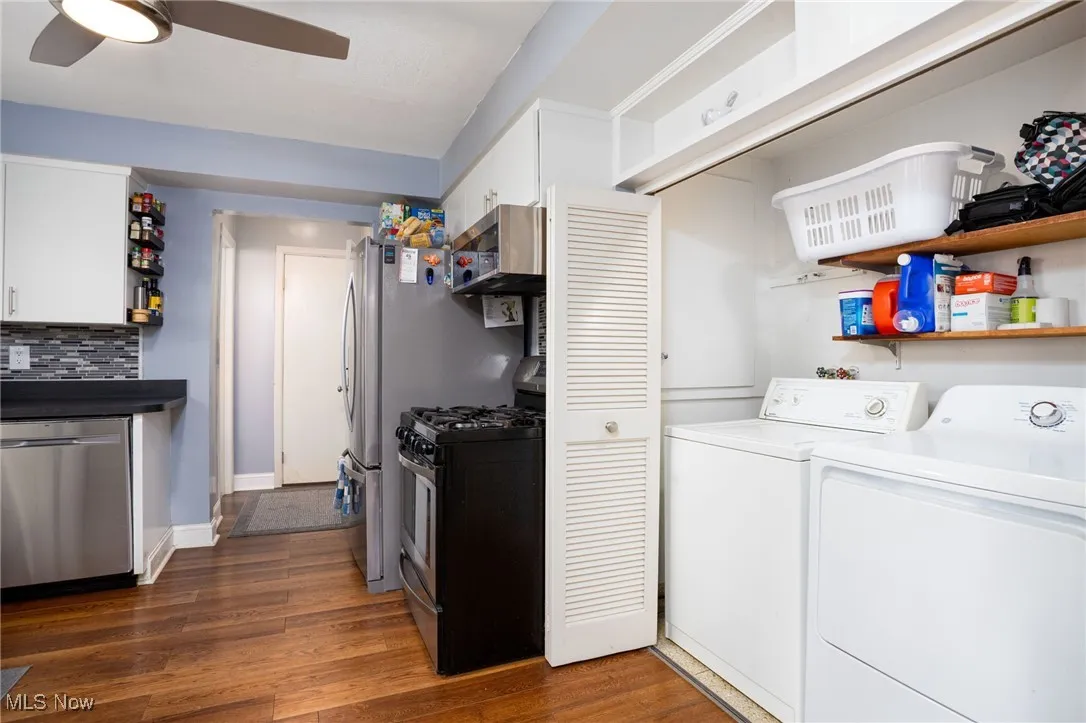 Laundry room with dark wood-style flooring, washing machine and dryer, and ceiling fan