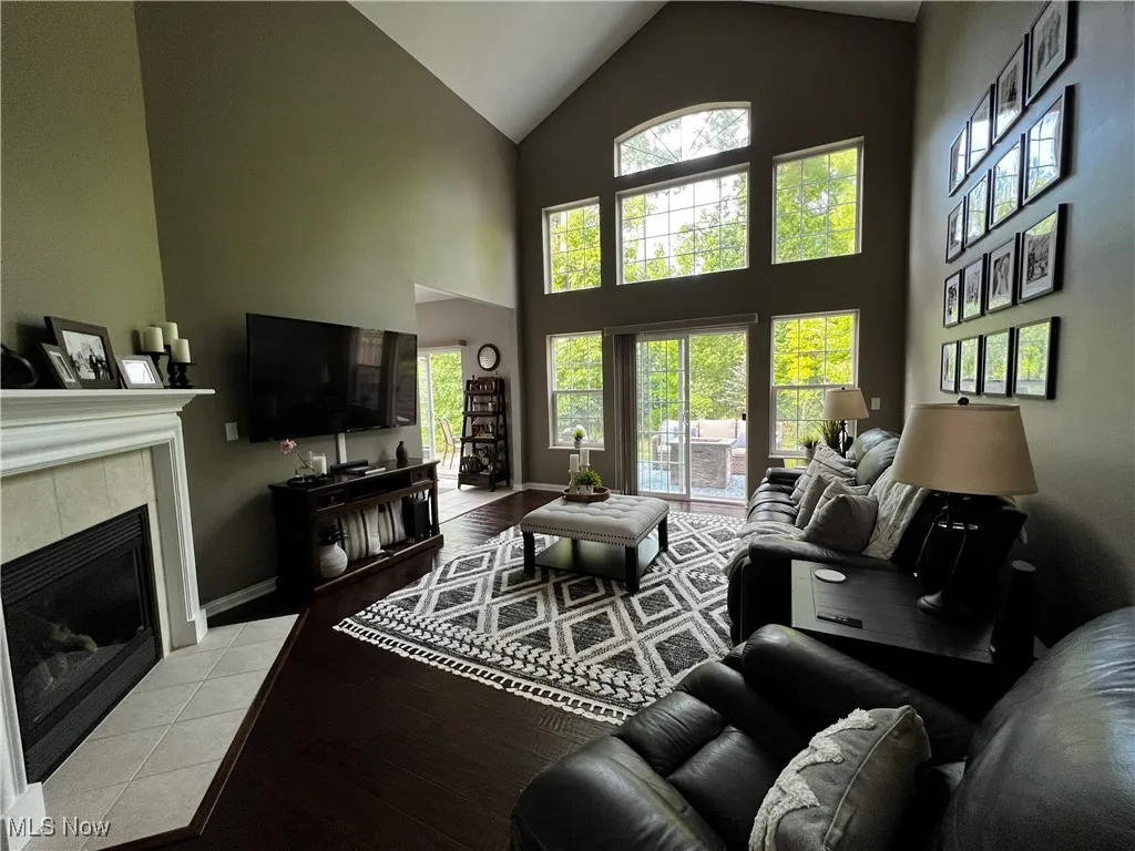 Living room featuring a tiled fireplace, plenty of natural light, light wood-style floors, and high vaulted ceiling