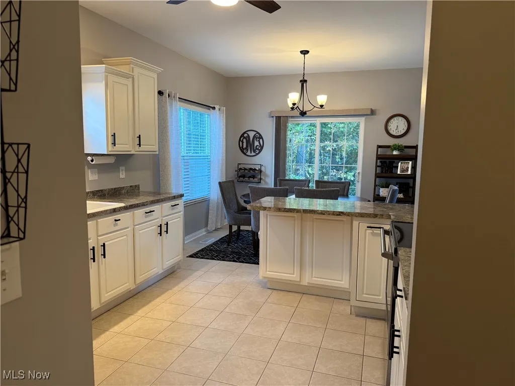 Kitchen with light tile patterned floors, white cabinets, and a peninsula