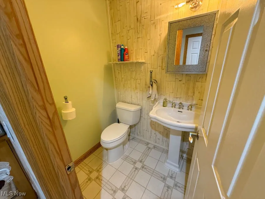 Half bath with wood walls and light tile patterned floors