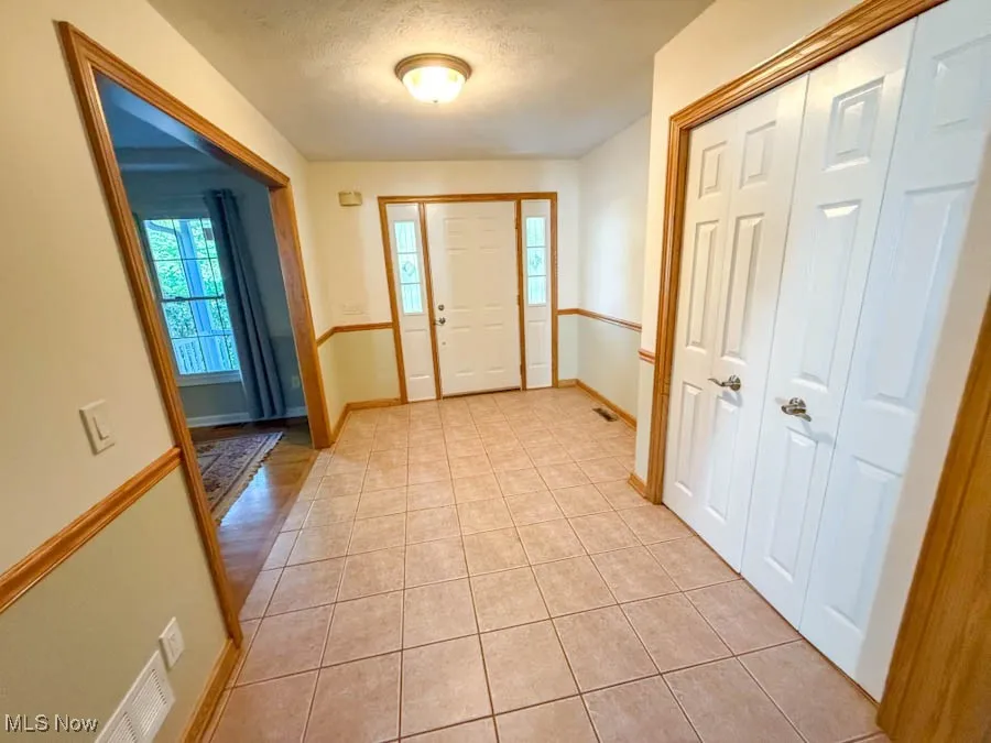 Foyer with light tile patterned flooring and a textured ceiling