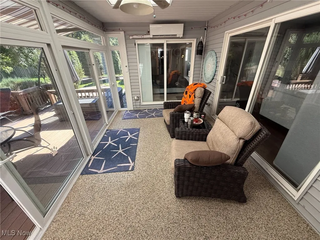 Sunroom featuring a ceiling fan and an AC wall unit