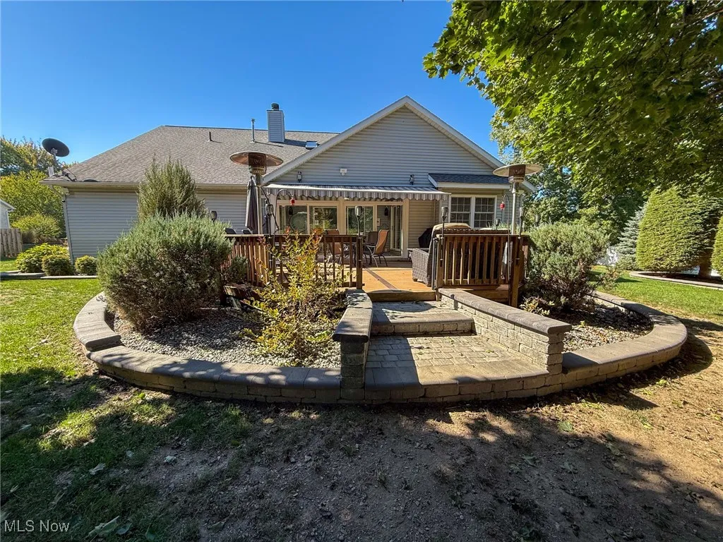 Rear view of house featuring a deck, a chimney, and a shingled roof