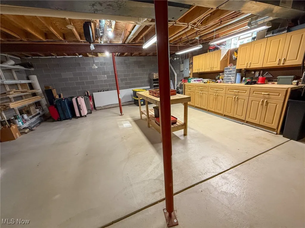 Unfinished basement featuring a workshop area and electric panel