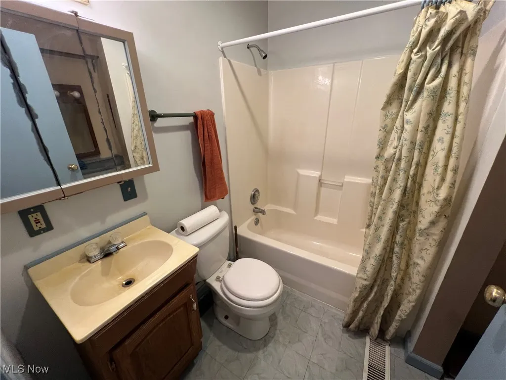 Bathroom featuring shower / bath combo with shower curtain and vanity