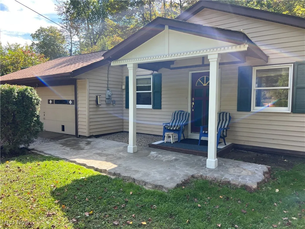 View of front of home featuring covered porch, a garage, and a front yard
