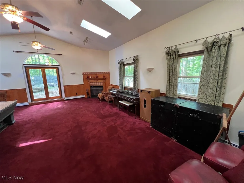 Living room featuring a skylight, dark colored carpet, vaulted ceiling, a tile fireplace, and plenty of natural light