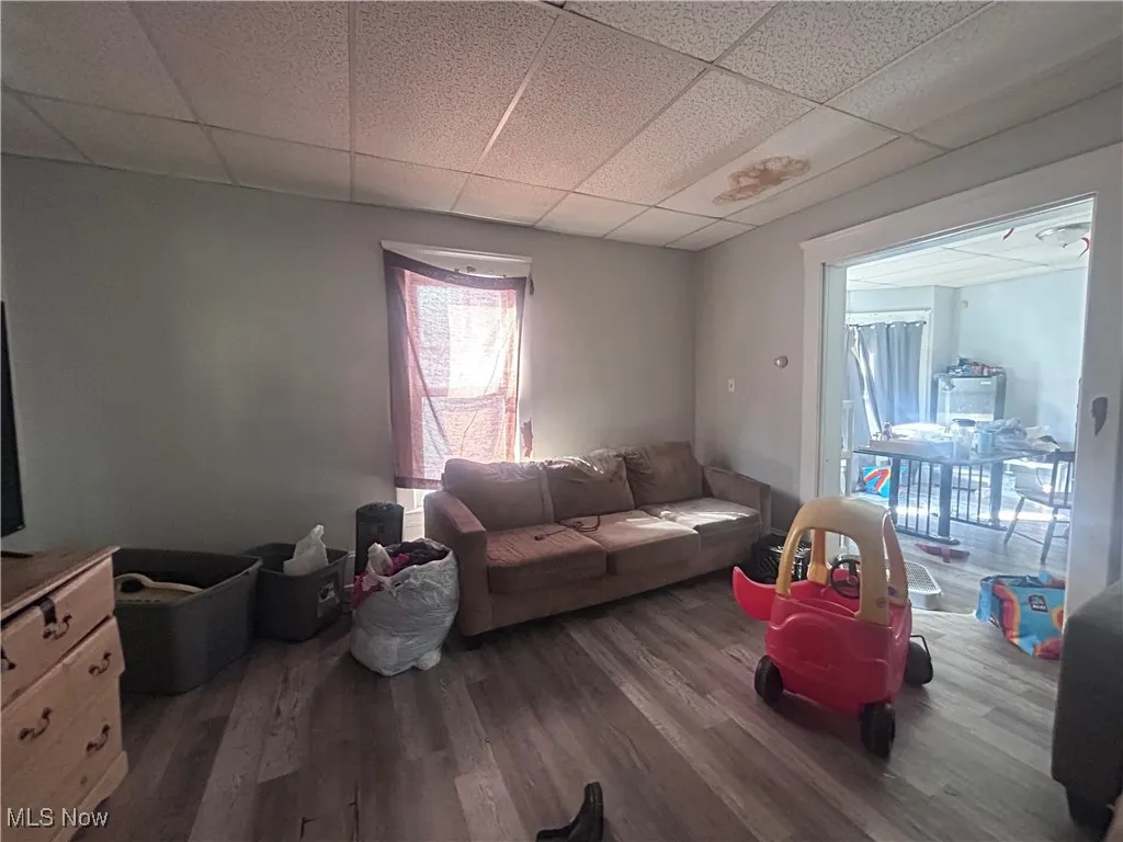 Living area with dark wood-style flooring and a paneled ceiling