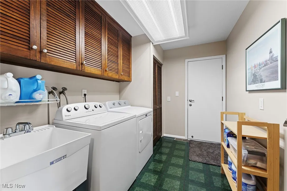 Laundry area featuring dark flooring, independent washer and dryer, and cabinet space